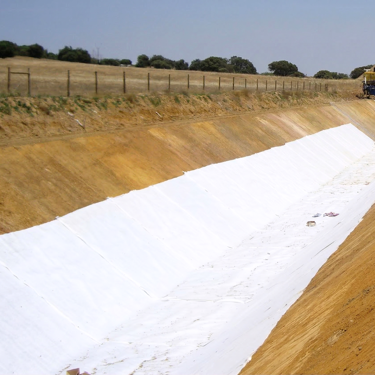 Installation d'une couverture drainante étendue sur le sol dans un canal ou une tranchée de chantier.