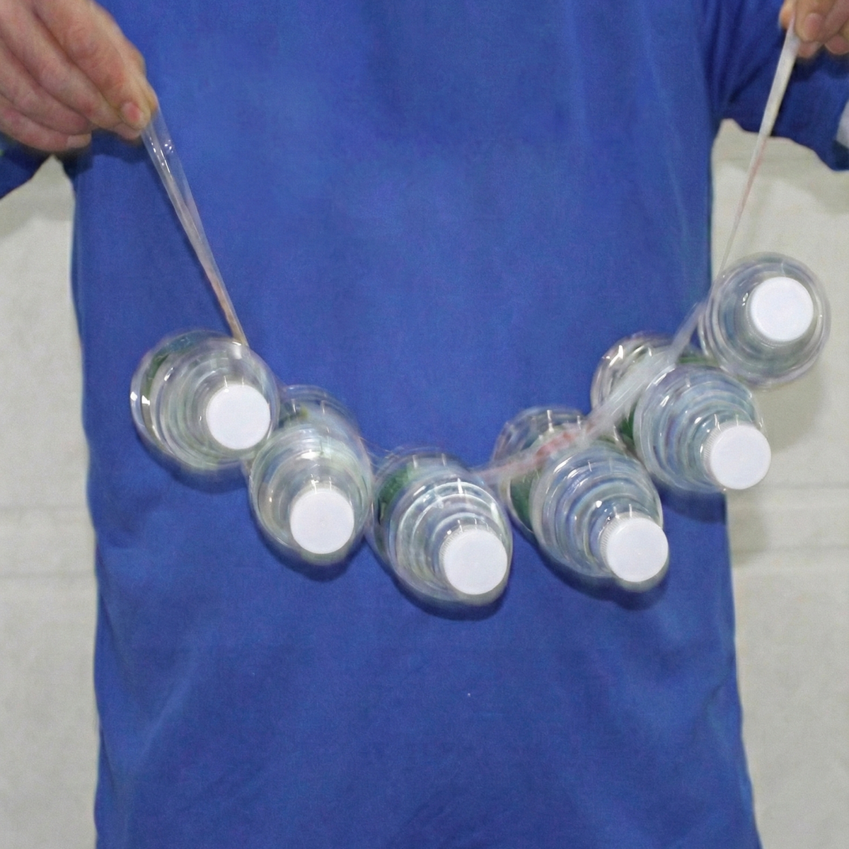 Demonstration of the plastic tape's adhesion holding multiple water bottles simultaneously.
