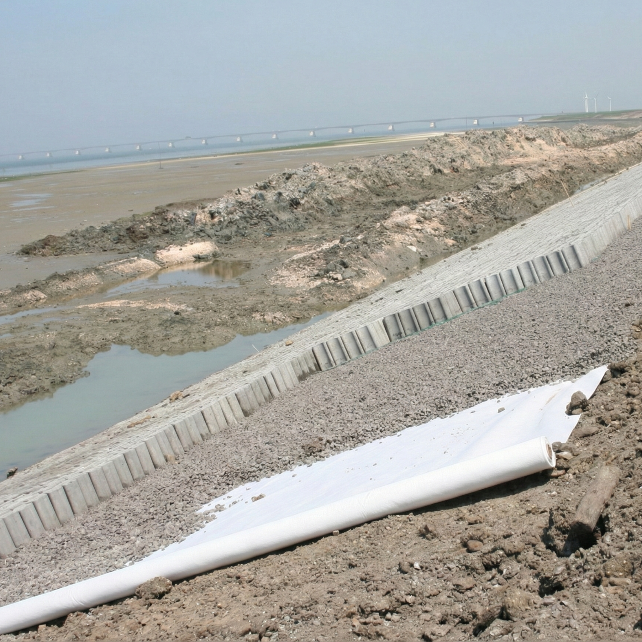 Geotextil no tejido de poliéster (PET) blanco aplicado en obra para separación de capas de suelo y refuerzo de drenaje.