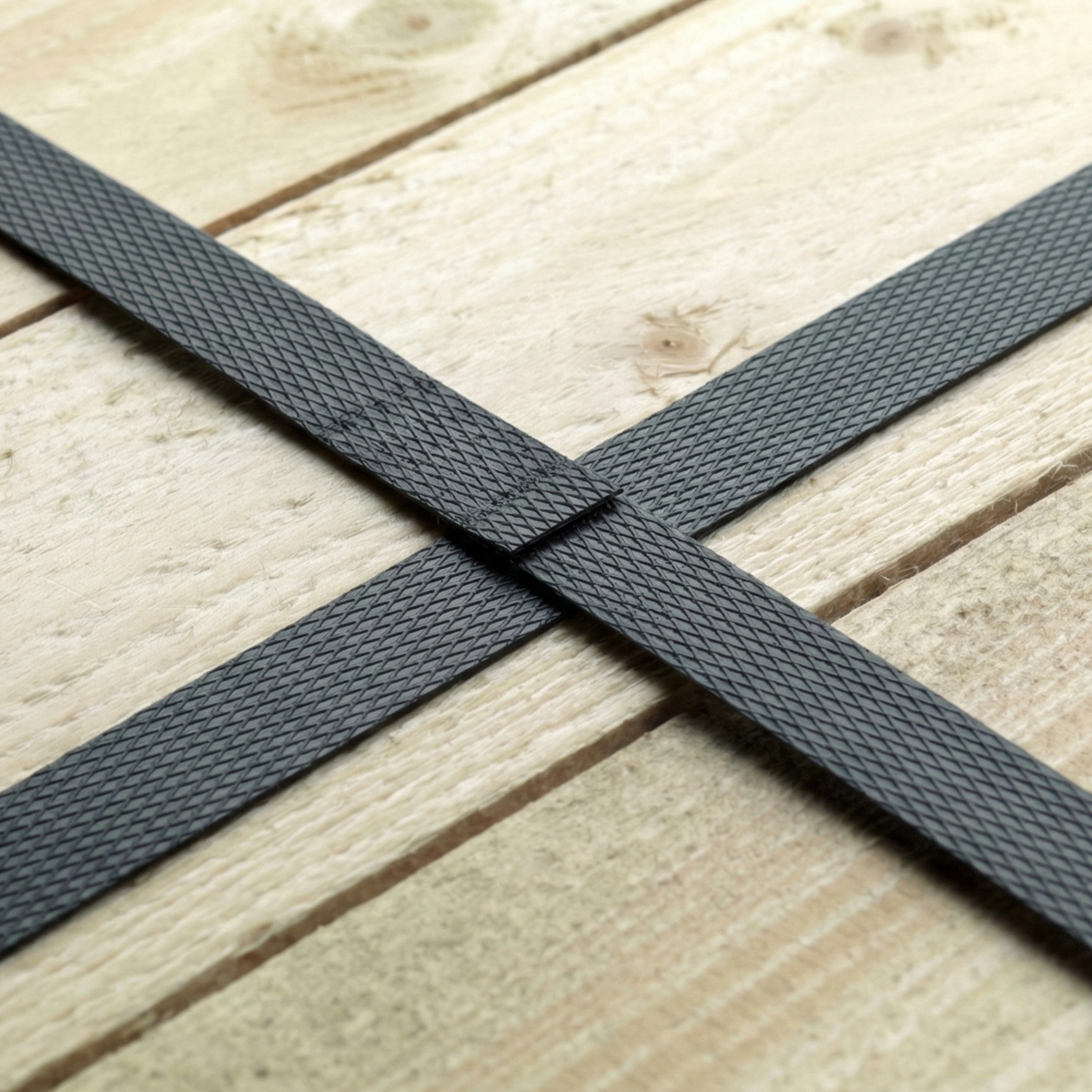 Black PP strap tensioned and cross-sealed over wood, ensuring the safety of palletized cargo in the Dominican Republic.