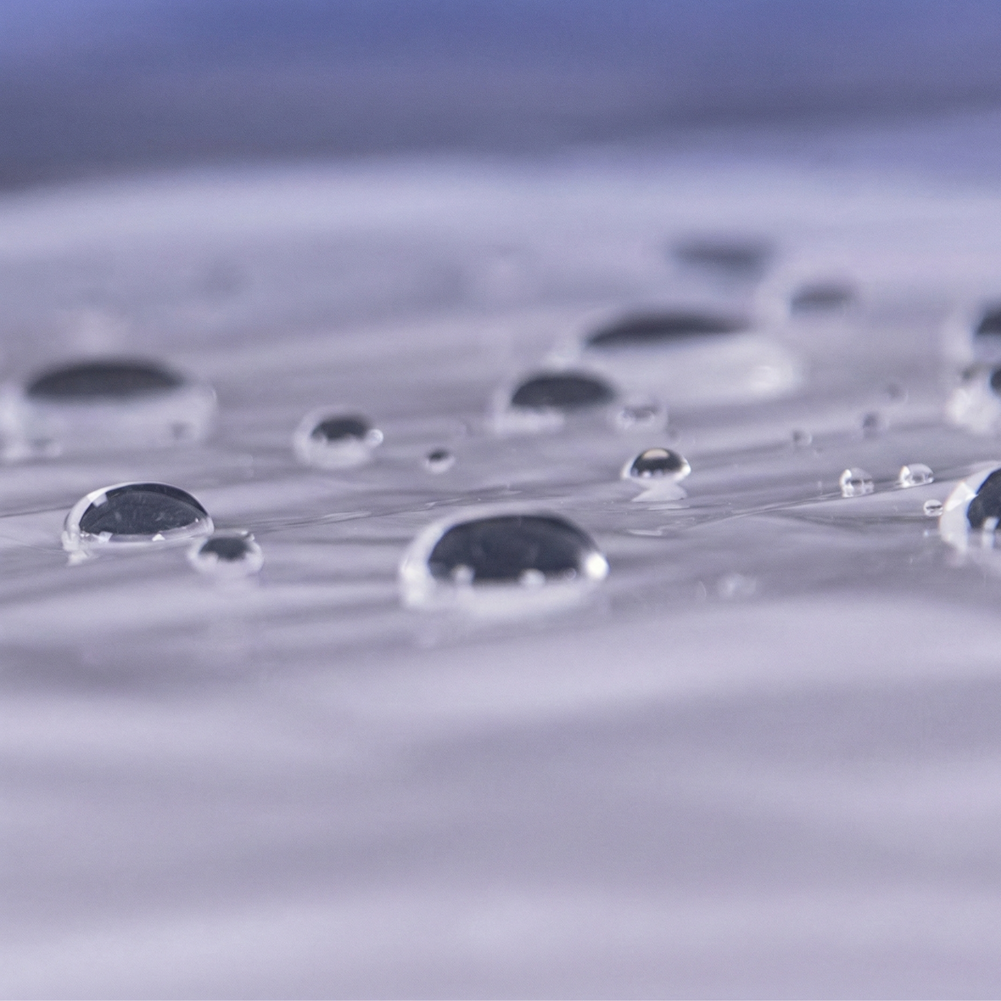 Superficie de stretch film con gotas de agua, demostrando la impermeabilidad y capacidad de protección contra la humedad de la película plástica para embalaje y logística.