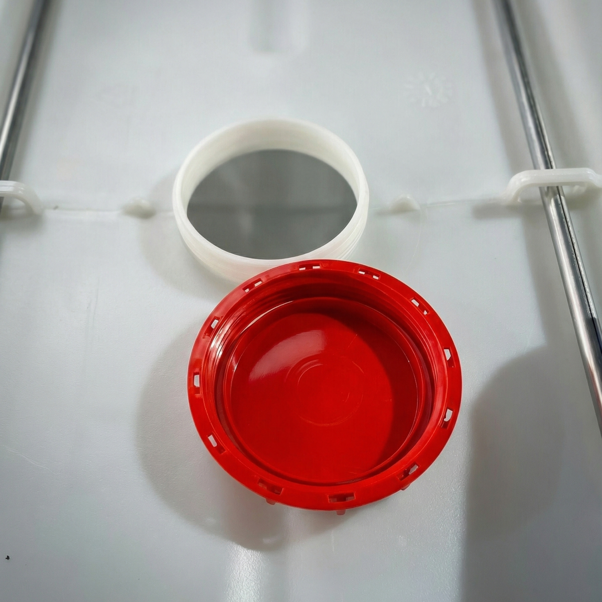 View of the open filling hatch and red upper lid of an IBC tank for packaging in the Dominican Republic.