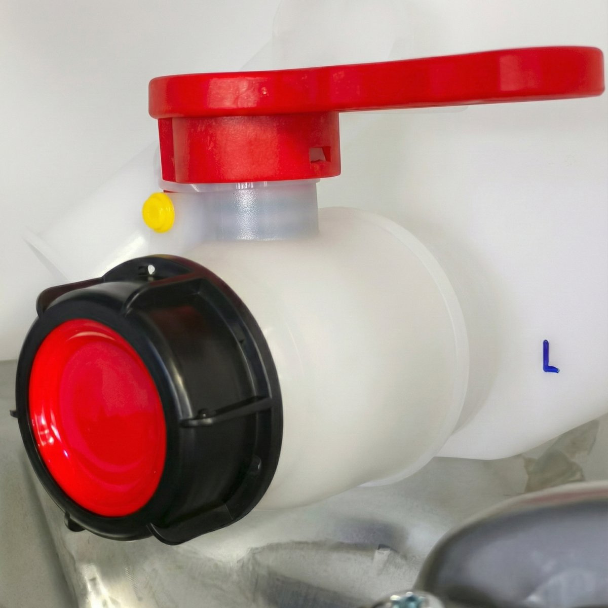 Close-up of the lower discharge valve with a red safety handle on an IBC container in Santiago, DR.