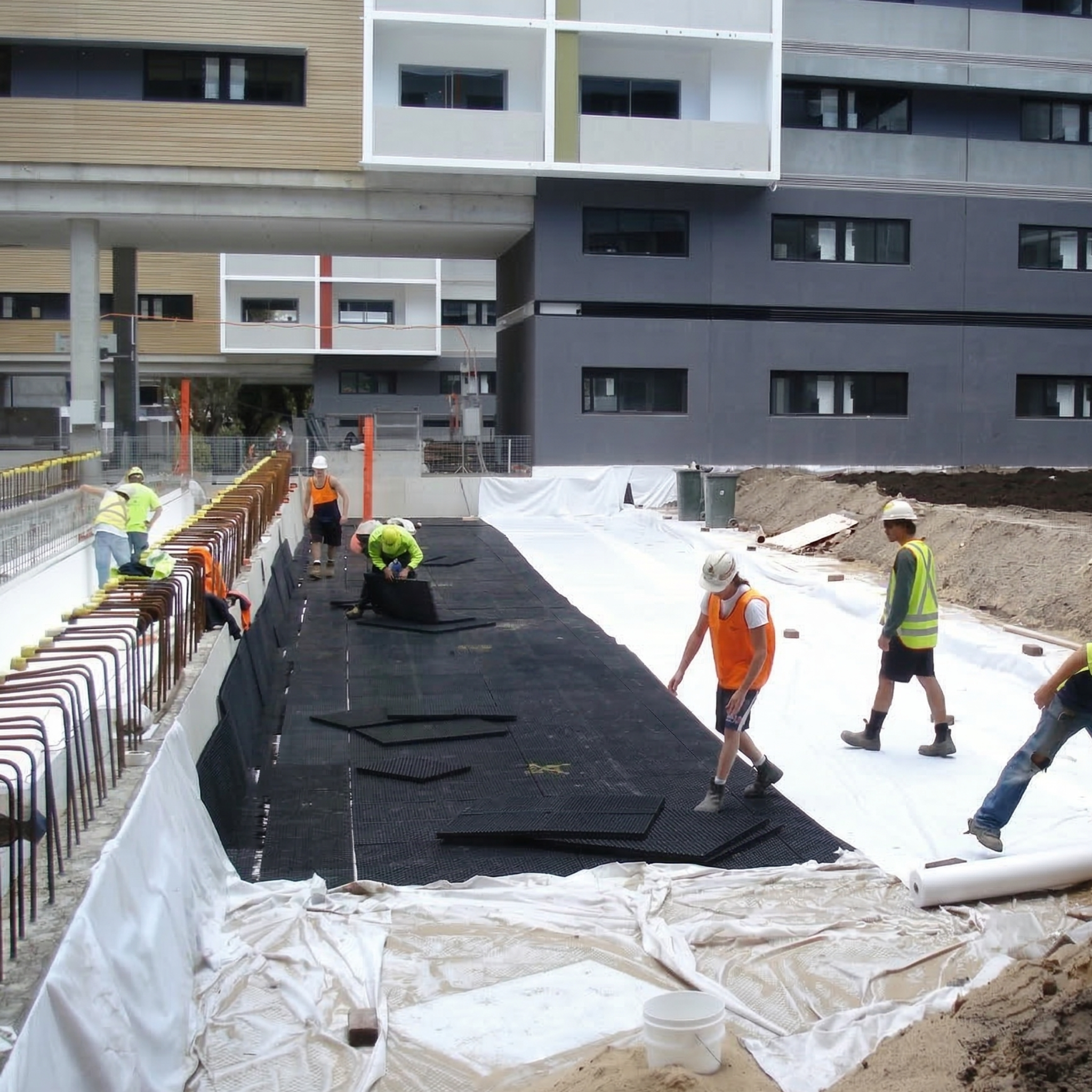 Ouvriers assemblant un système de drainage modulaire sur un chantier de construction.