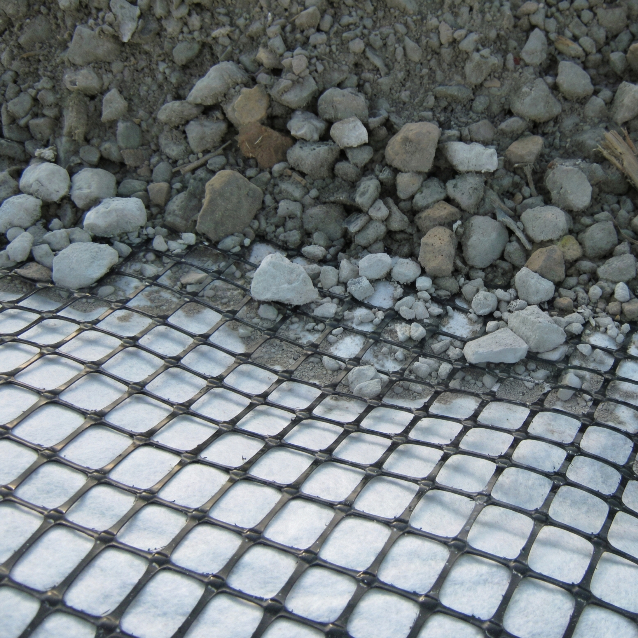 Detalle de geomalla biaxial colocada sobre geotextil y cubierta con grava para optimización de pavimentos en República Dominicana.