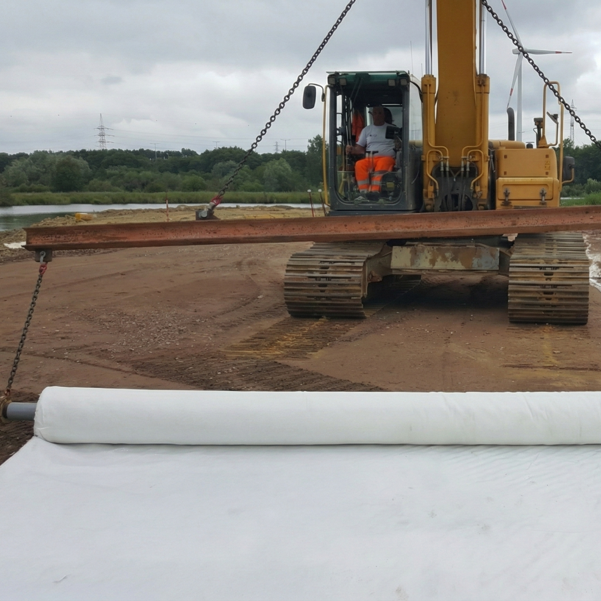 Heavy machinery installing a roll of white woven geotextile for soil separation and subgrade reinforcement in the Dominican Republic.