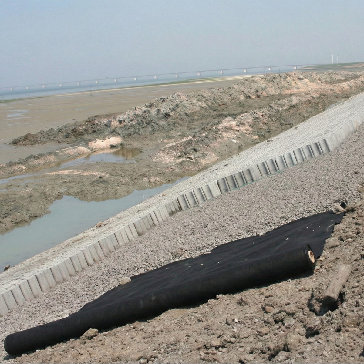 Geotextil no tejido de polipropileno (PP) negro instalado en obra para separación de suelos y protección de geomembranas.